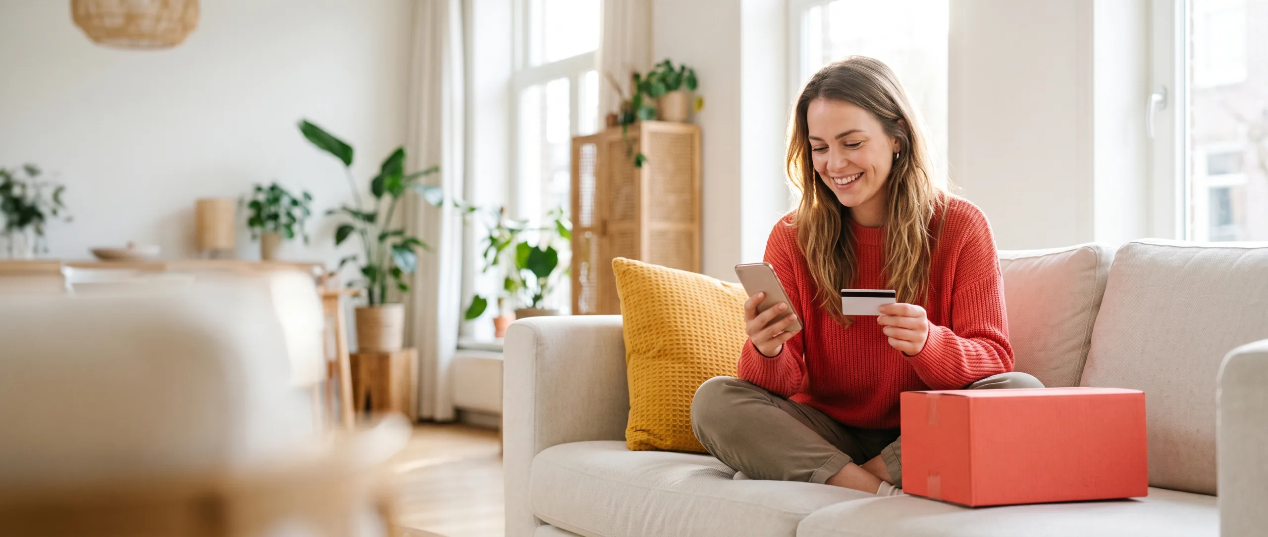 Vrouw op de bank die blij online winkelt met haar telefoon