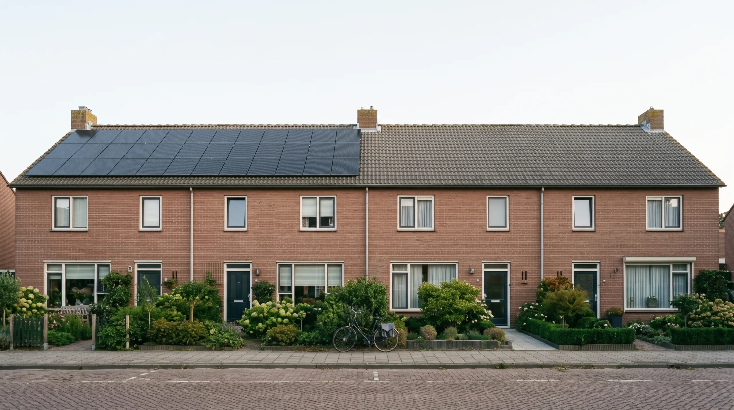 Twee Nederlandse rijtjeshuizen naast elkaar, één met zonnepanelen op het dak